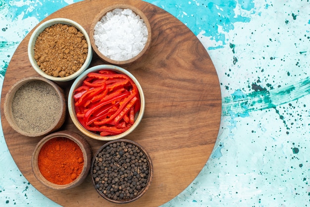 Top view sliced red pepper with salt pepper and different seasonings on the light-blue background pepper salt product color photo