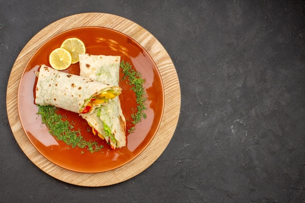 Top view of sliced shaurma delicious meat sandwich inside brown plate on black