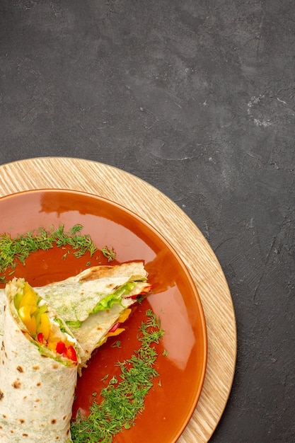 Foto gratuita vista dall'alto del delizioso panino di carne shaurma affettato all'interno del piatto marrone su nero