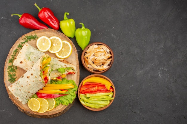 Top view of sliced shaurma tasty meat sandwich with lemon slices on black