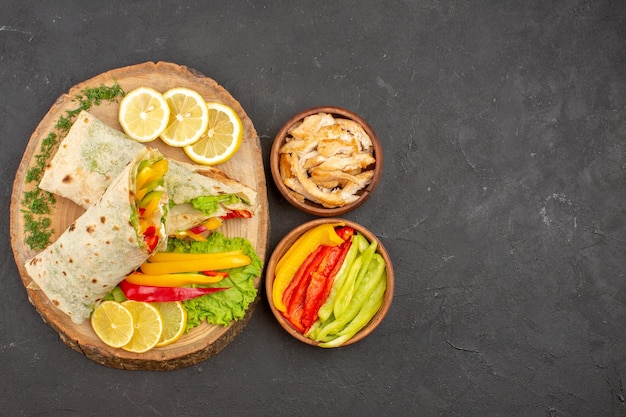 Foto gratuita vista dall'alto del gustoso sandwich di carne shaurma affettato con fette di limone su nero