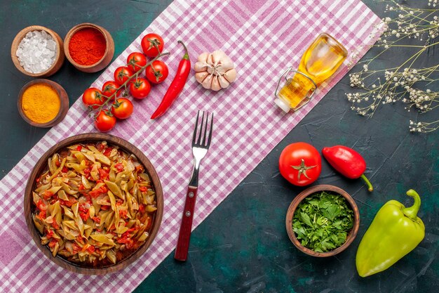 Top view sliced vegetable meal with different seasonings on dark blue background