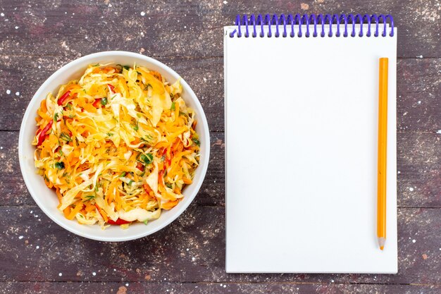 Top view sliced vegetable salad fresh and salted inside plate with notepad on the brown rustic wooden desk vegetable food meal dish fresh photo