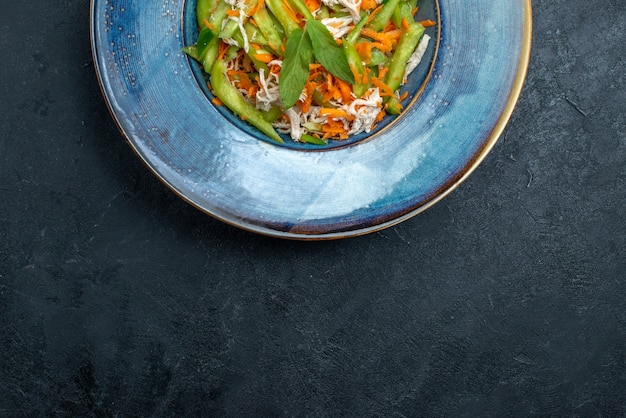 Top view sliced vegetable salad inside plate on the dark grey background