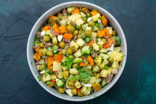 Top view sliced vegetable salad peppered with chicken slices inside plate on the dark-blue desk salad vegetable meal snack lunch