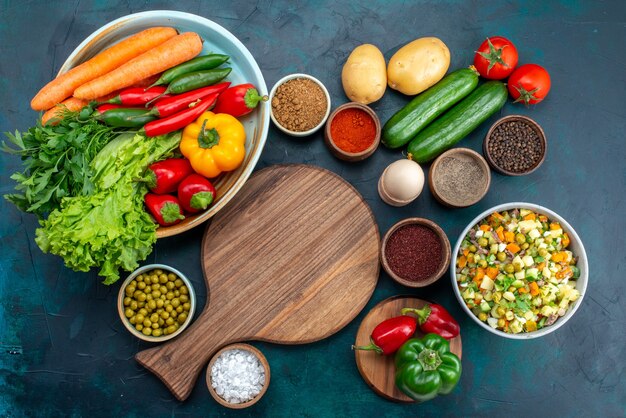 Top view sliced vegetable salad peppered with chicken slices inside plate with fresh vegetables on the blue desk snack lunch salad vegetable food