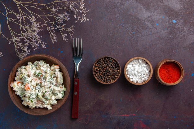 Top view sliced vegetable salad with mayyonaise and chicken along with seasonings on a dark background salad meal food snack lunch