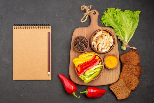 Top view of sliced vegetables with black bread loafs on black