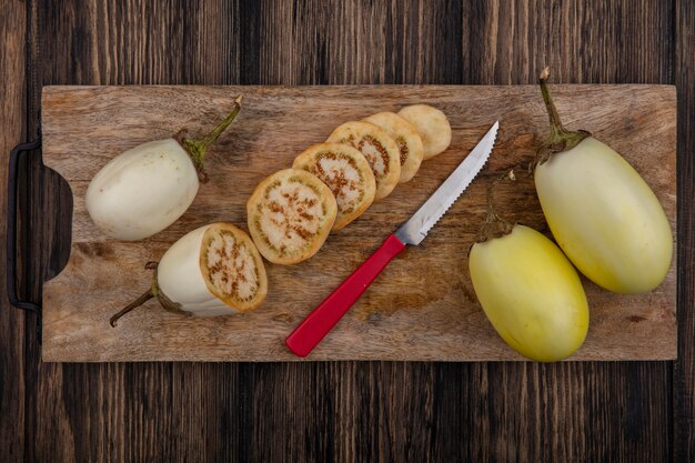 Top view sliced white eggplant with knife on cutting board on wooden background