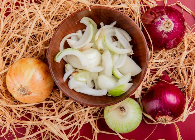 Free photo top view of sliced white onion in bowl with sweet, red and whole white one on straw and red