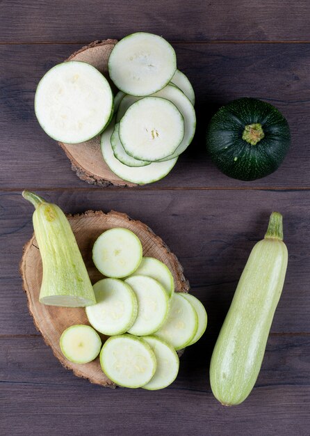 Top view sliced zucchinis on stubs and dark wooden table.