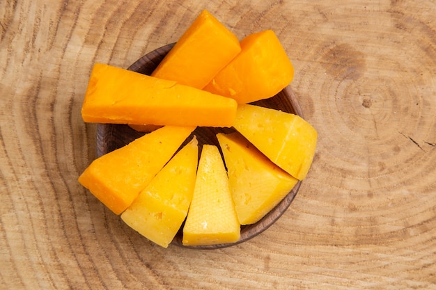 Free photo top view slices of cheese in bowl on wooden table