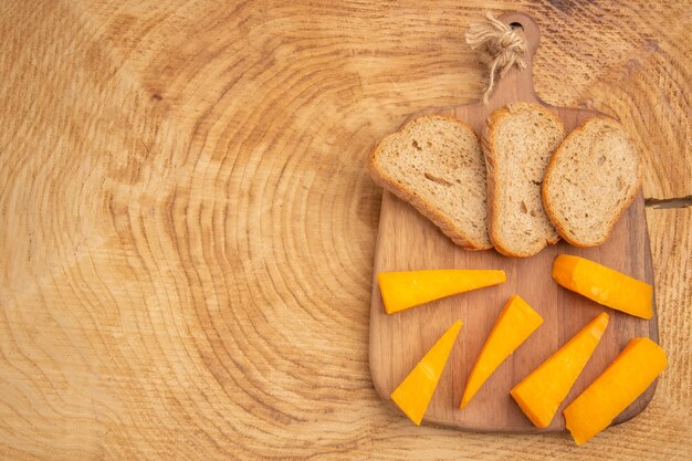 Top view slices of cheese slices of bread on cutting board on wooden table with copy space