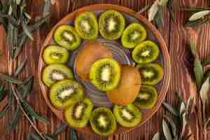 Free photo top view of slices of kiwi fruit on a plate on wood