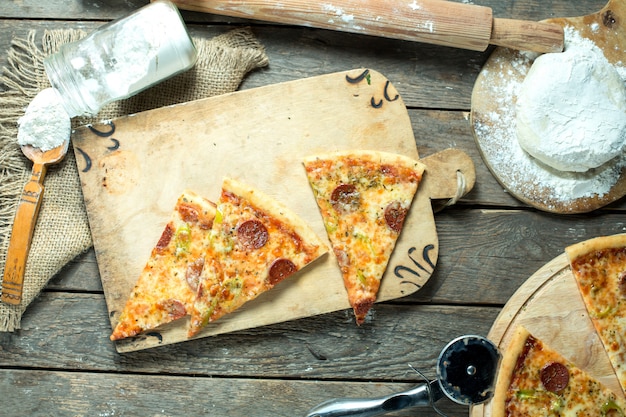 Top view of slices of pizza salami with tomato sauce green chili pepper and spices