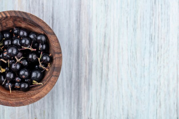 Top view of sloe berries in bowl on wooden surface
