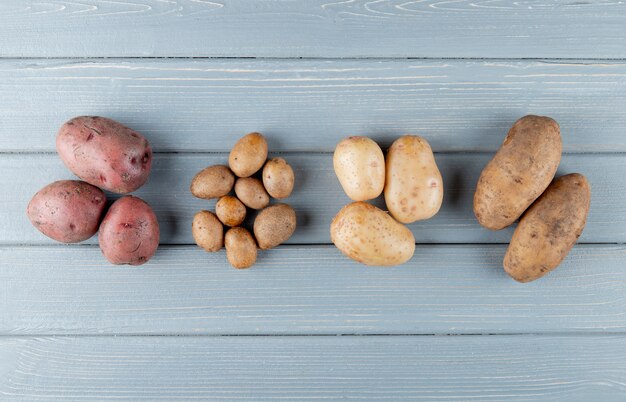 Top view of small and big potatoes on wooden background with copy space