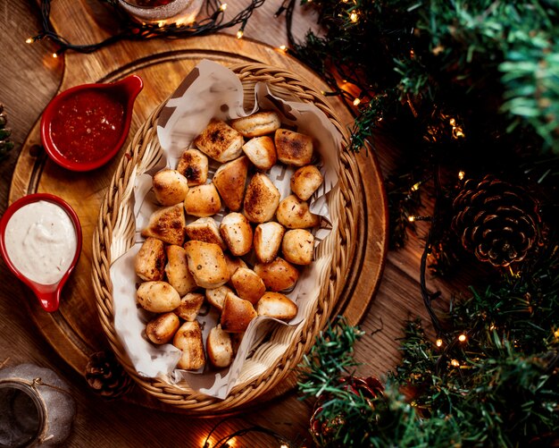 Top view small garlic breads basket served with tomato sauce and mayonnaise