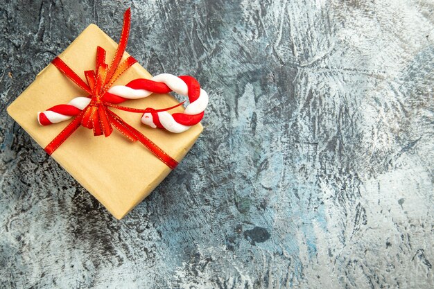 灰色の表面に赤いリボンのクリスマスキャンディーで結ばれた上面図の小さな贈り物