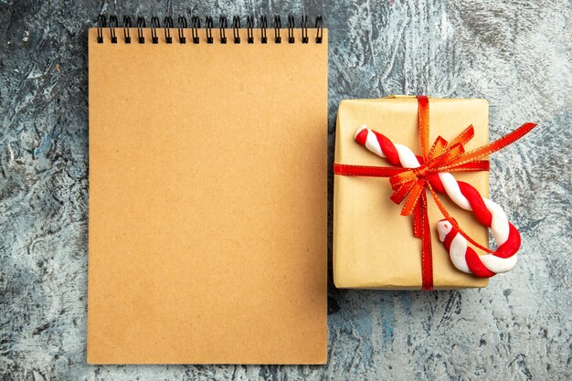 灰色の背景に赤いリボンのクリスマスキャンディーノートブックで結ばれた上面図の小さな贈り物