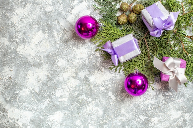 Foto gratuita vista dall'alto piccoli regali rami di pino albero di natale giocattoli su superficie grigia