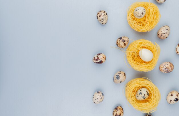 Top view of small quail eggs with cream colored shells on a nest on a white background with copy space