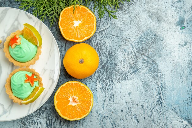 접시에 녹색 과자 크림과 레몬 슬라이스 상위 뷰 작은 타르트 복사 공간이 어두운 테이블에 오렌지를 잘라