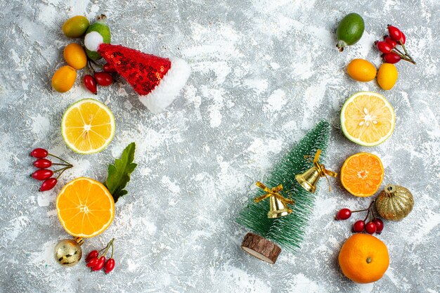 Top view small xmas tree feijoas cut lemons xmas hat on grey table free space