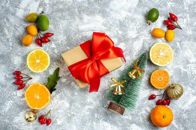 상위 뷰 작은 크리스마스 트리 크리스마스 선물은 회색 테이블에 레몬 페이조아스 개 로즈힙을 잘라냅니다. 무료 사진