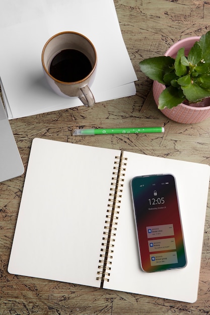 Top view of smartphone on desk with coffee cup and notebook