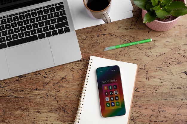 Top view of smartphone on desk with coffee cup and notebook