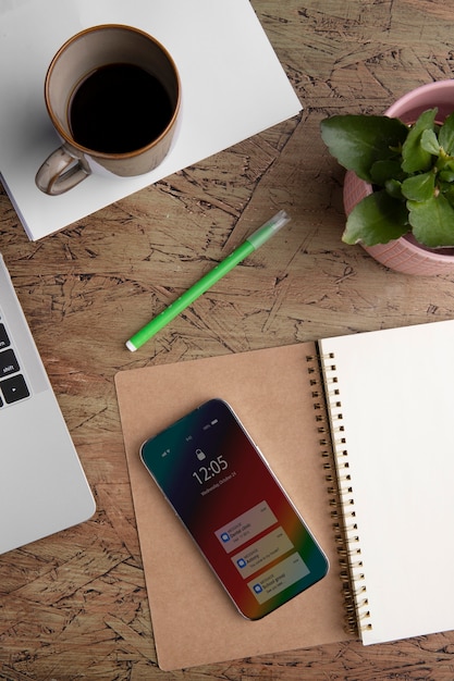 Top view of smartphone on desk with coffee cup and notebook