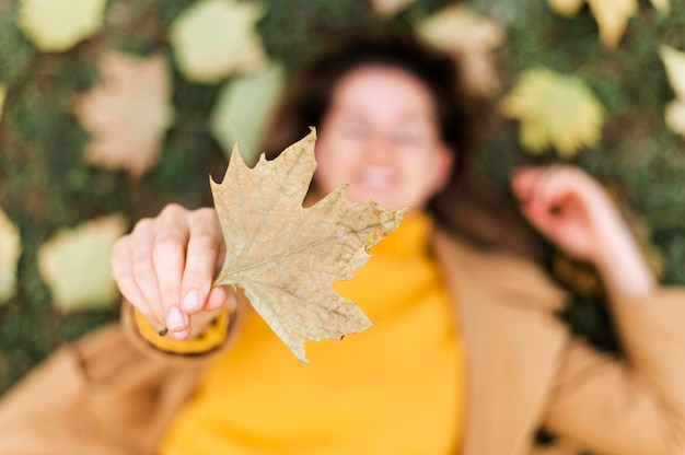 Top view smiley woman staying on the ground while holding a leaf