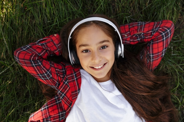 Free photo top view of smiling young brunette girl lying on grass