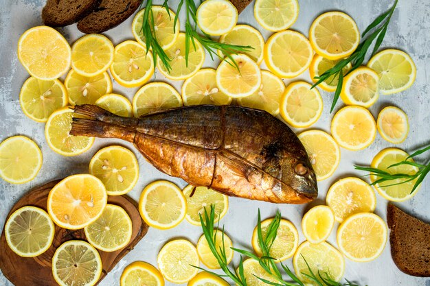 Top view of smoked fish surrounded with lemon slices