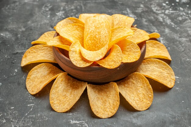 Top view of snack party for friends with delicious potato chips on gray background