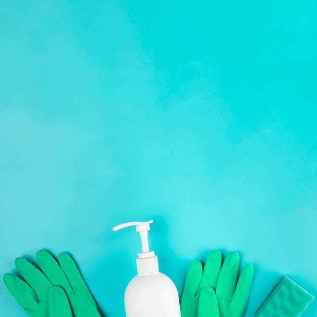 Top view soap bottles and gloves on blue background