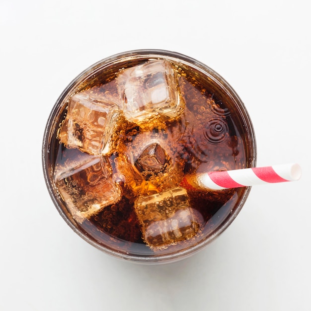 Free photo top view of soft drink in glass with ice cubes and straw