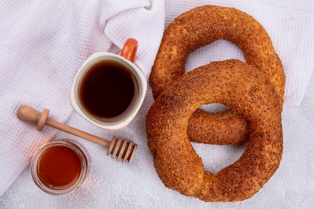 Top view of soft traditional turkish bagels with a cup of tea and honey on a glass jar on a white background