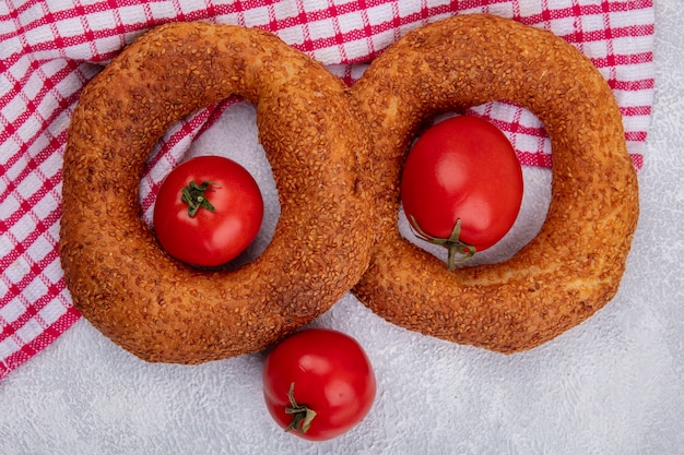 Top view of soft traditional turkish bagels with fresh tomatoes on a red checked cloth on a white background