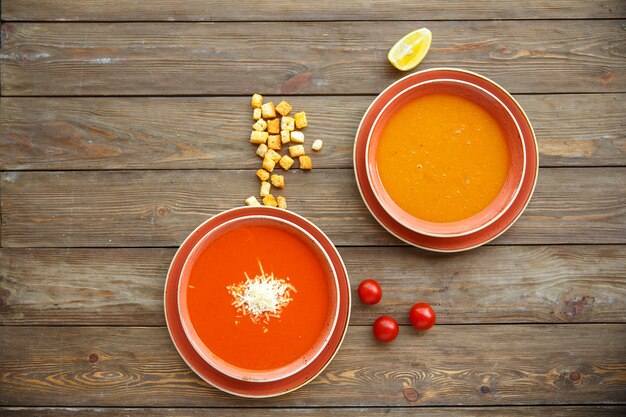 Top view of soup bowls with tomato and lentil soups in wooden background