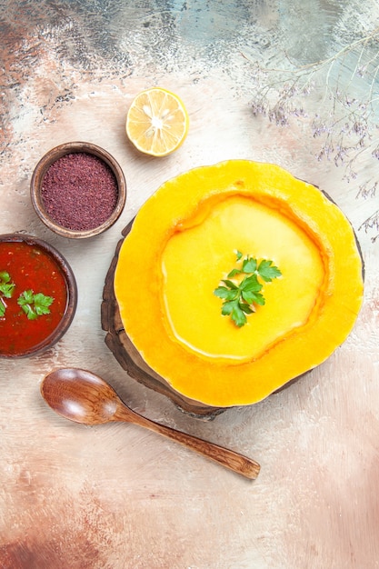 Foto gratuita vista dall'alto del cucchiaio da minestra zuppa di zucca al limone sulle spezie salsa bordo