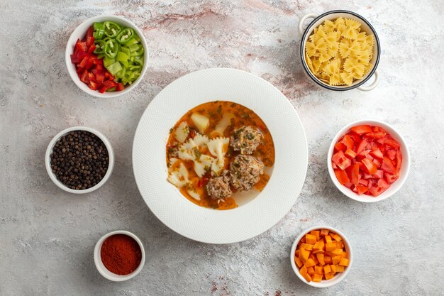 白い背景にスライスした野菜と調味料を使った肉のおいしいスープの上面図スープ