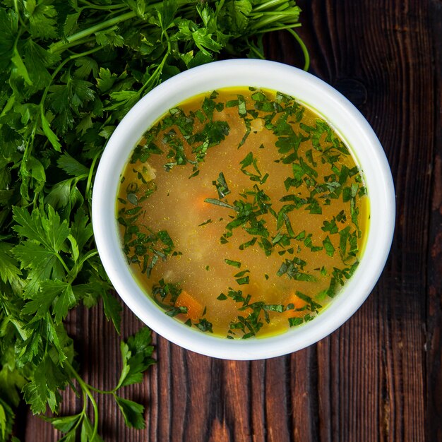 Top view soup with vegetables and parsley in a white plate