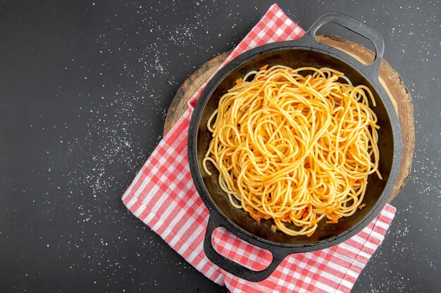 Top view spaghetti frying pan on wood board on dark background