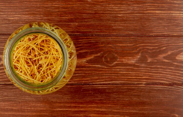 Top view of spaghetti pasta in bowl on wooden surface with copy space