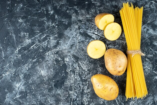 Top view of spaghetti with potatoes on light-gray surface
