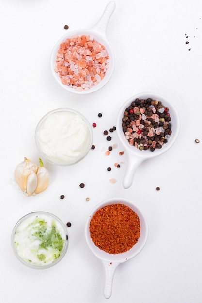 Free photo top view spices salt papper with garlic and white yogurt on white  vertical