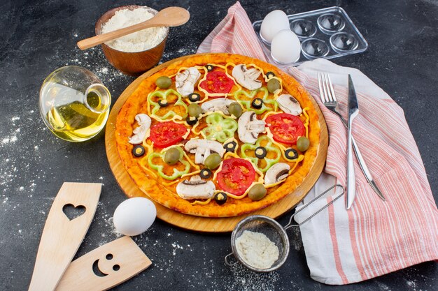 Top view spicy mushroom pizza with red tomatoes bell peppers olives all sliced inside with oil and flour on the grey desk food pizza dough