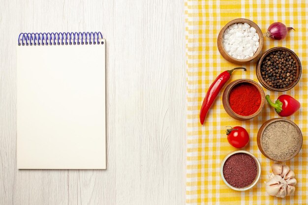 Top view of spicy seasonings with vegetables on white